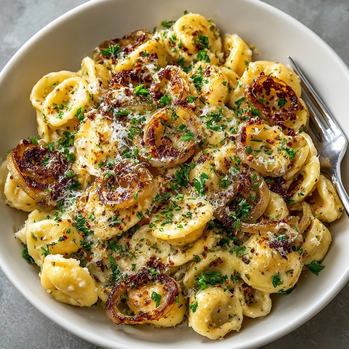 Easy French Onion Pasta topped with melted Gruyere, creamy sauce, and caramelized onions in a skillet