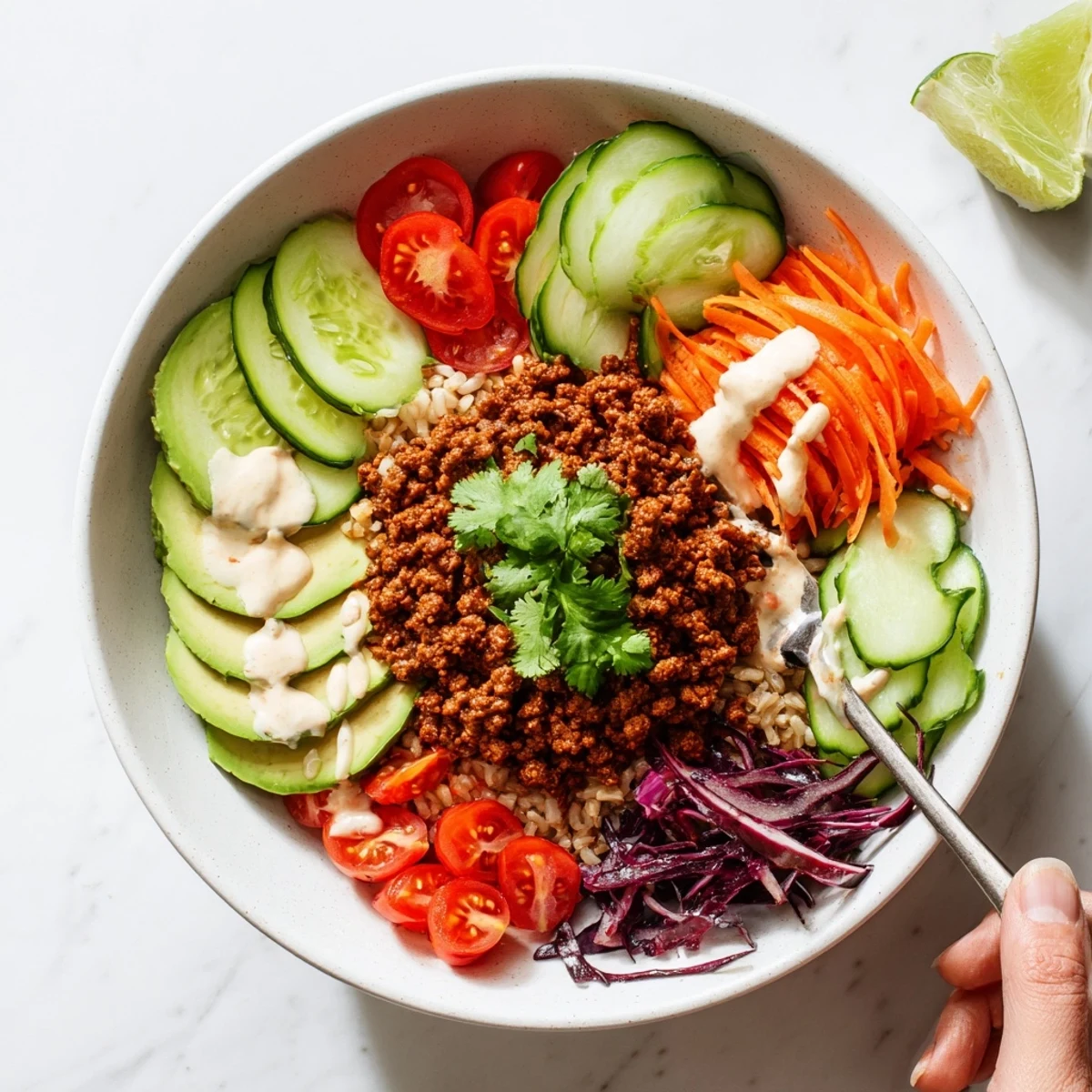 Savory plant-based meat bowl topped with creamy avocado and tangy lime wedges.