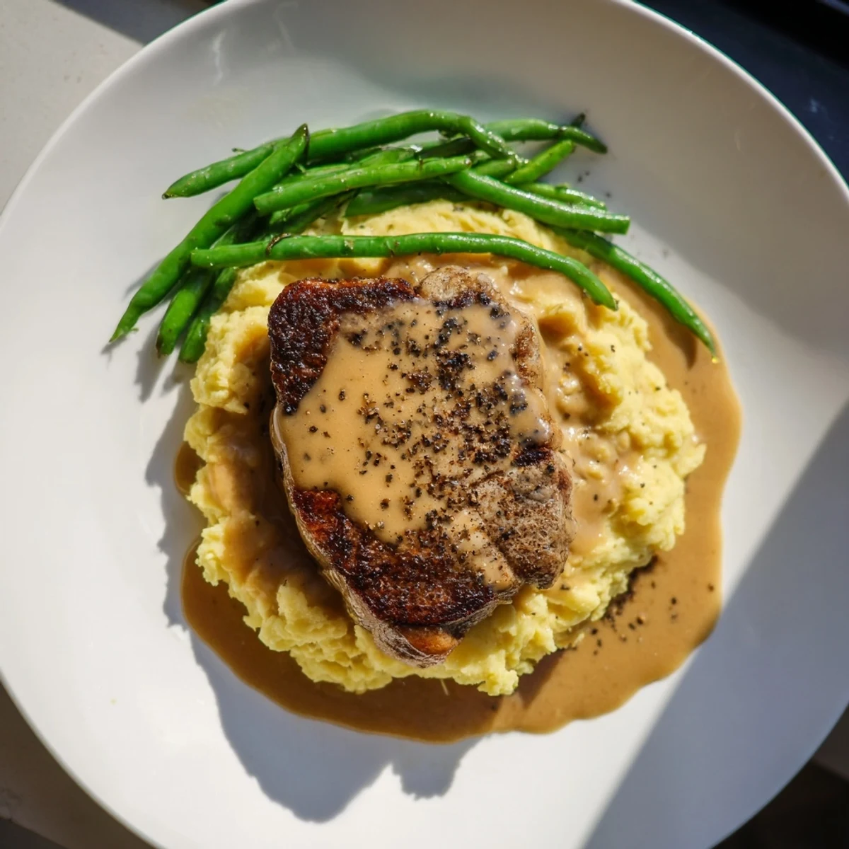 Sizzling pork chops sit atop creamy cheddar mashed potatoes in this comforting Pork Chops & Cheddar Mash Bowl.