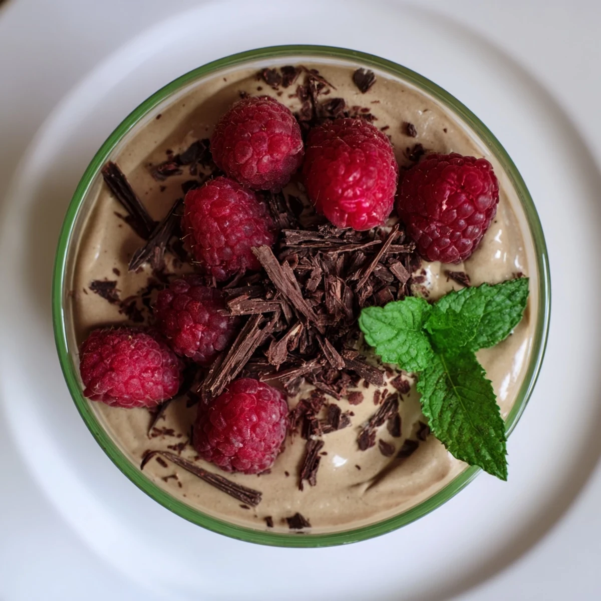 Velvety smooth avocado chocolate mousse served in individual glasses, topped with bright red raspberries.