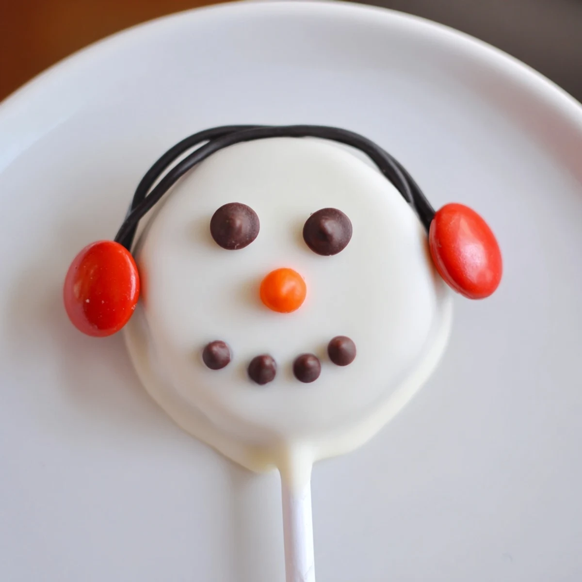 Melted white chocolate covers the Oreo cookies to create these fun Budget-Friendly Oreo Snowman Pops.
