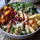 Bright pomegranate seeds and crunchy pepitas top a hearty Kale Harvest Grain Bowl, drizzled with tangy maple Dijon dressing.