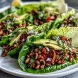 Golden sautéed black-eyed peas mixed with shredded carrots and cherry tomatoes, neatly folded into tender romaine lettuce wraps for a refreshing bite.