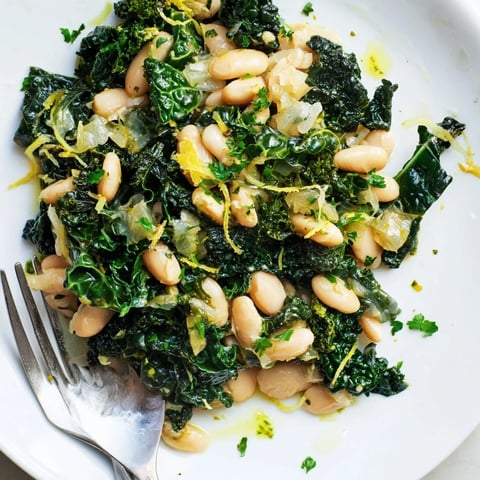 A steaming bowl of Garlicky Beans with Winter Greens, a fragrant and healthy Mediterranean meal.