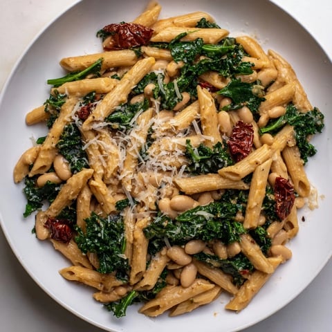 A vibrant photo of Healthy Tuscan White Bean & Kale Pasta, served steaming with fresh lemon zest.