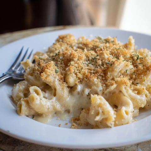 Golden-brown topping on a baked Lightened Mac & Cheese, with bubbly cheese and snowflake pasta.
