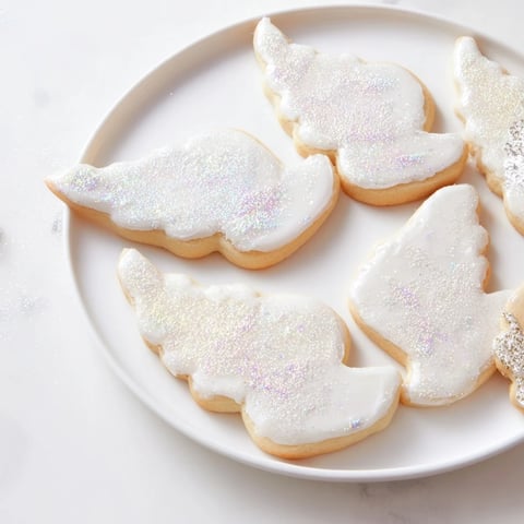 A plate piled high with golden Angel Wings sugar cookies, iced and sparkling with edible glitter.