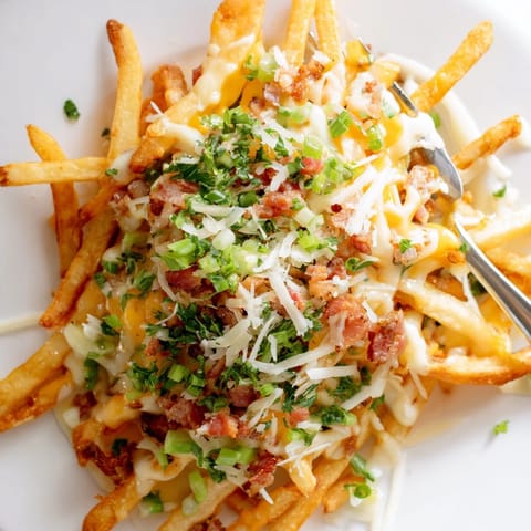 Indulgent truffle oil loaded fries bake, bursting with cheese, bacon, and fresh parsley.  