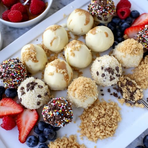Colorful array of cheesecake bites, drizzled with caramel and sprinkled with nuts.  