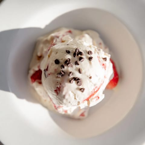 Homemade cottage cheese ice cream, swirled with fresh berries, looks cool and refreshing on a spoon.