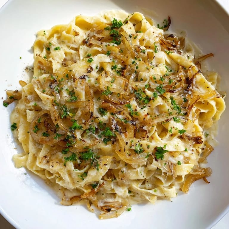 A warm bowl displays the delicious One-Pot French Onion Pasta, creamy and topped with melted Gruyère cheese.