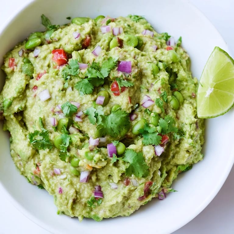 Close-up of chunky edamame guacamole, showing the creamy avocado texture and colorful vegetables.